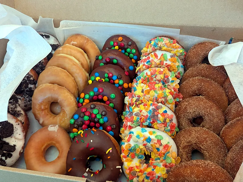 Box of fresh donuts with M&M, Fruity Pebbles and chocolate frosted