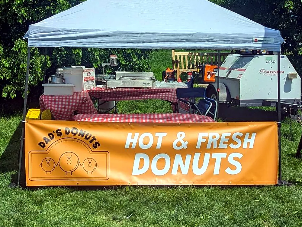 Close-up of the Dad's Donuts cart under its tent with the Hot and Fresh Donuts banner