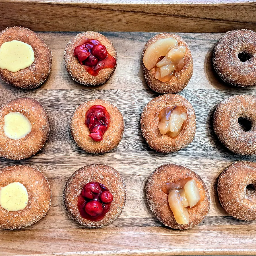 Tray of apple cider donuts with cream, cherry and apple fillings