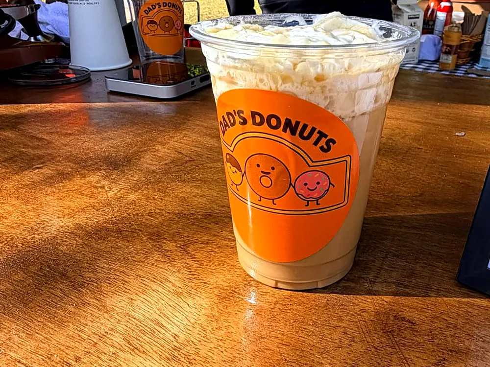 Iced latte in a Dad's Donuts cup from the barista cart