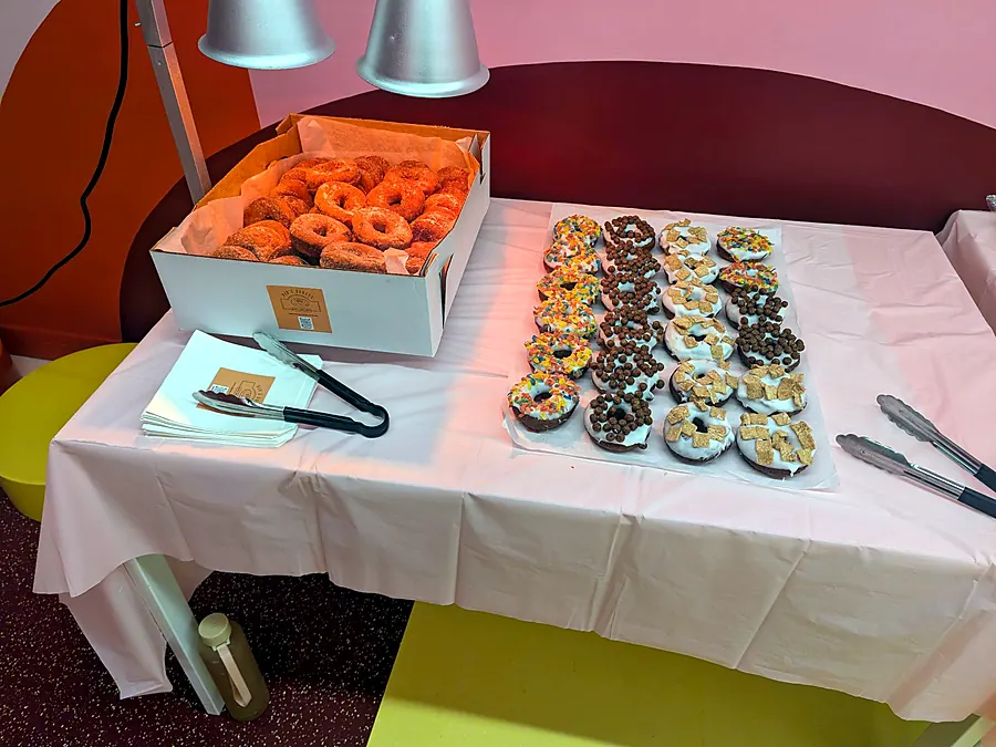 Donut table at an event with a box of cinnamon sugar donuts and a tray of topped donuts