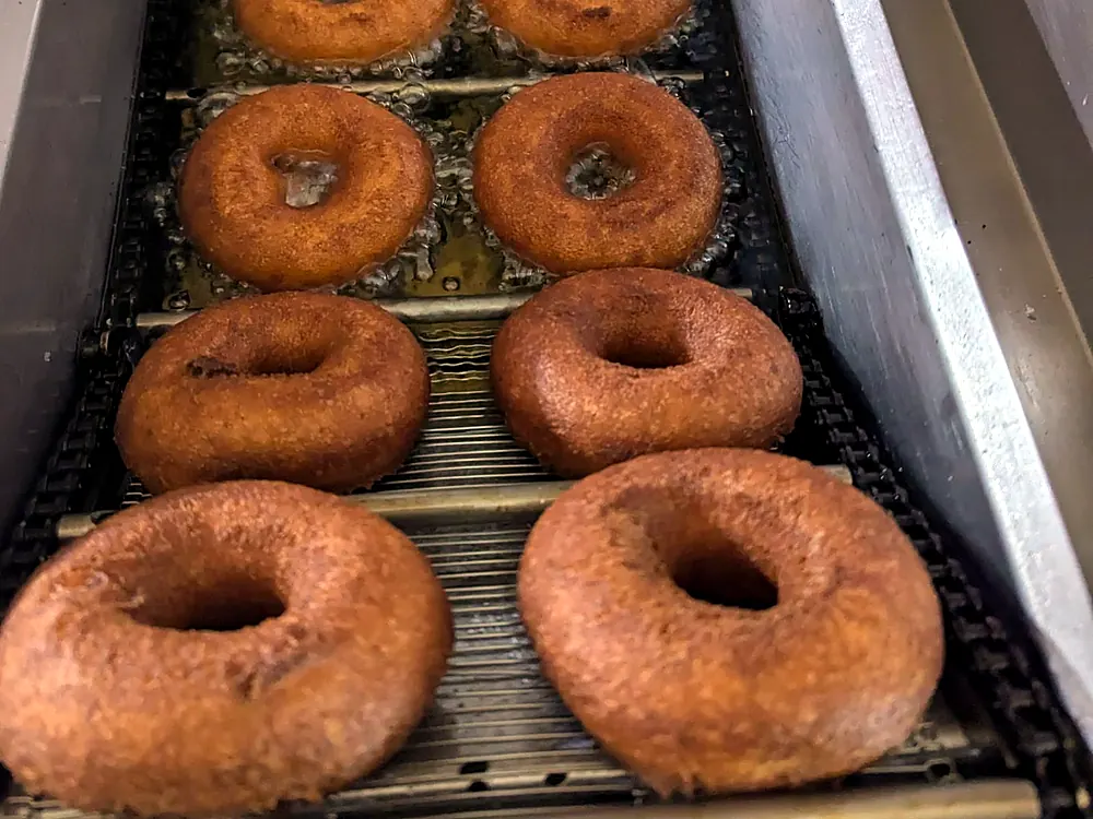 Apple cider donuts frying on the conveyor of our fryer
